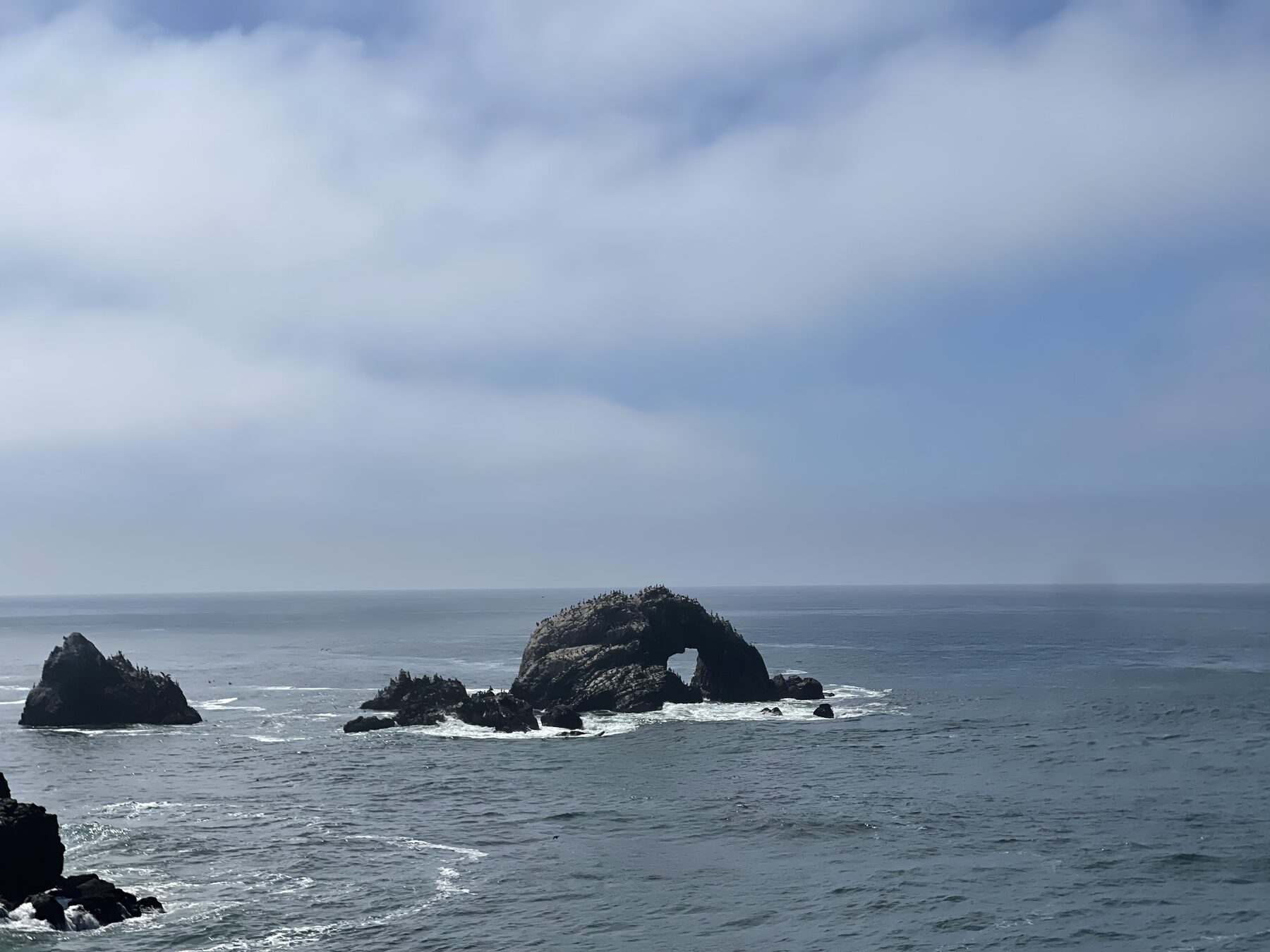 Offshore rocks under a cloudy sky.