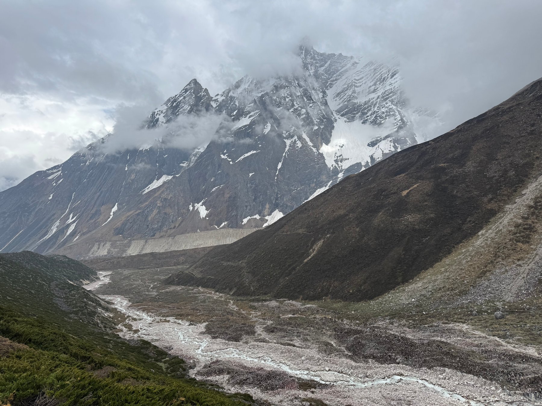 A rocky riverbed beneath snow-covered peaks.